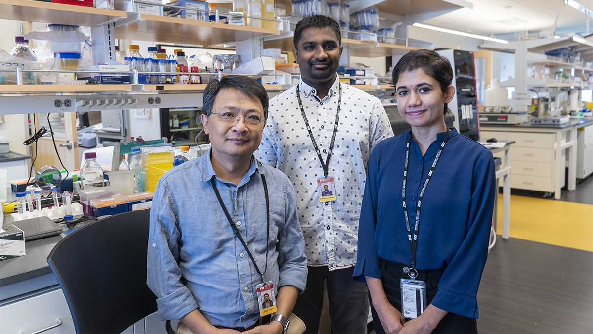 Three researchers pose for a group photo in a lab setting.