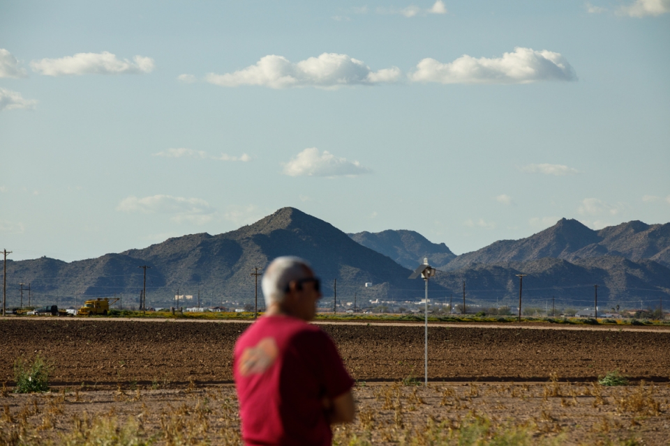 Scott in blurred foreground and dirt field and mountains in focus in background