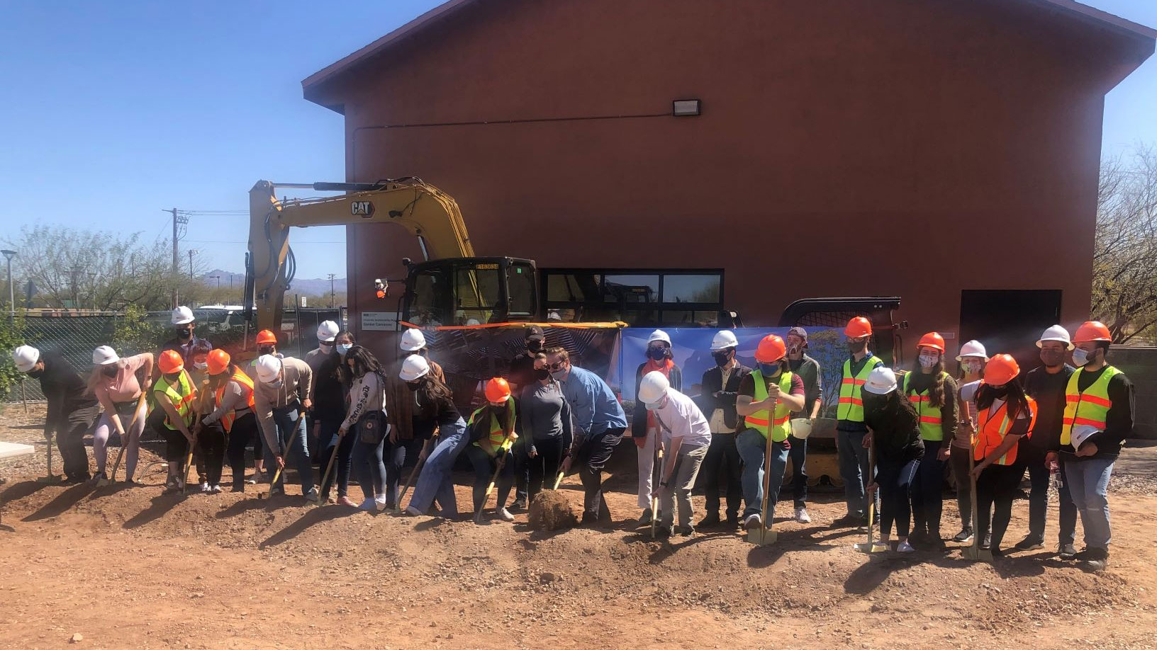 A line of ASU architecture students break ground on an outdoor classroom project
