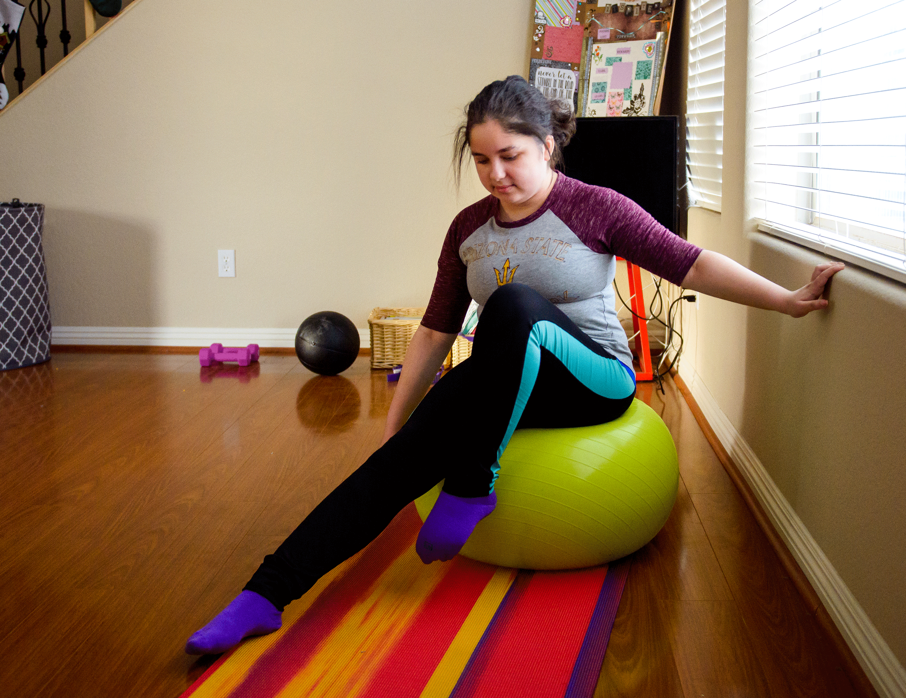 Maya Rodriguez does physical therapy on an exercise ball in her living room
