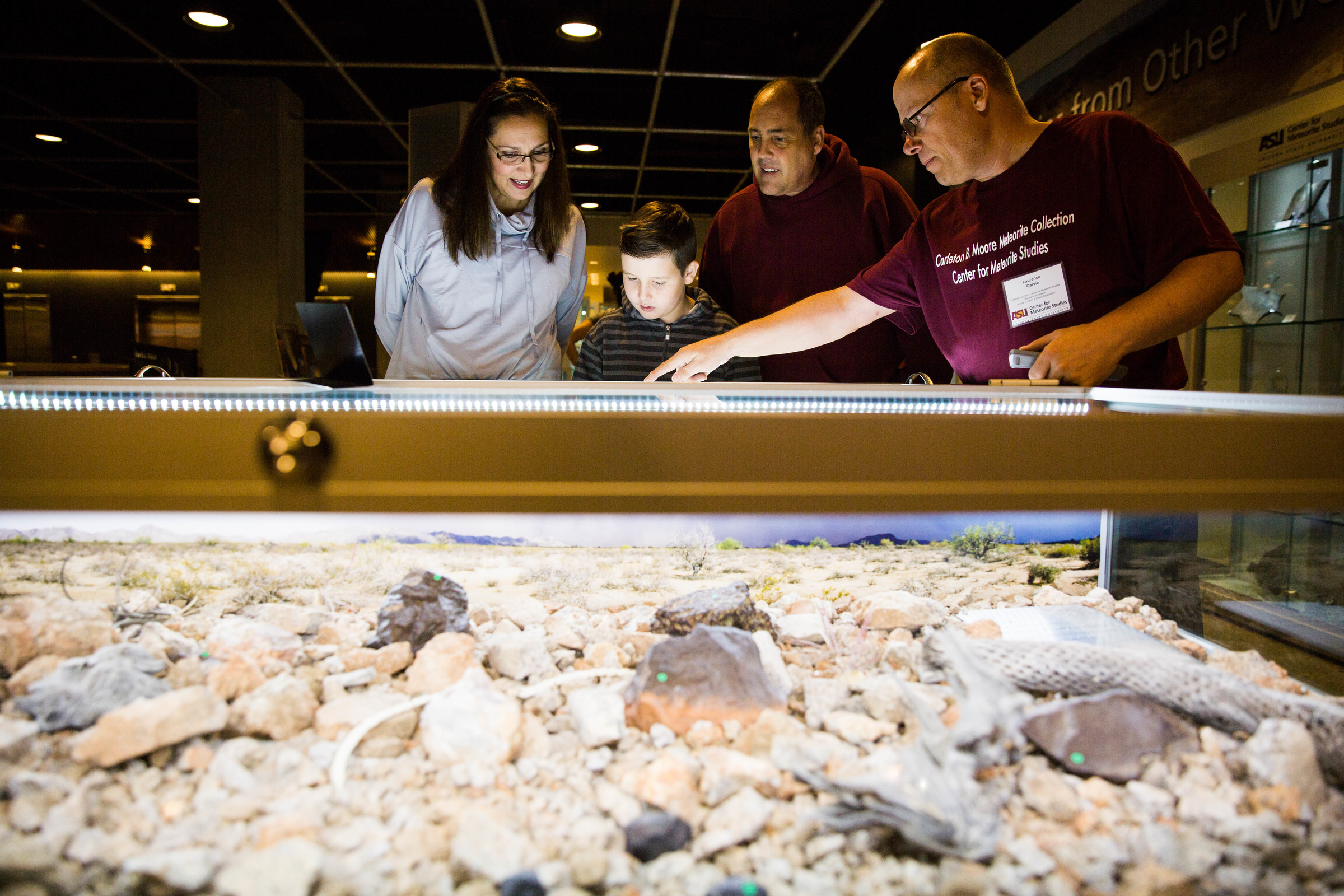 A family looks at a meteorite display.