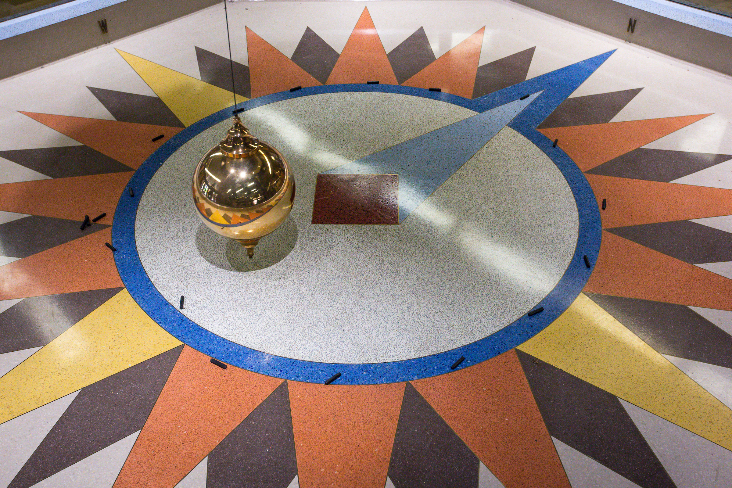 A giant pendulum moves across a floor