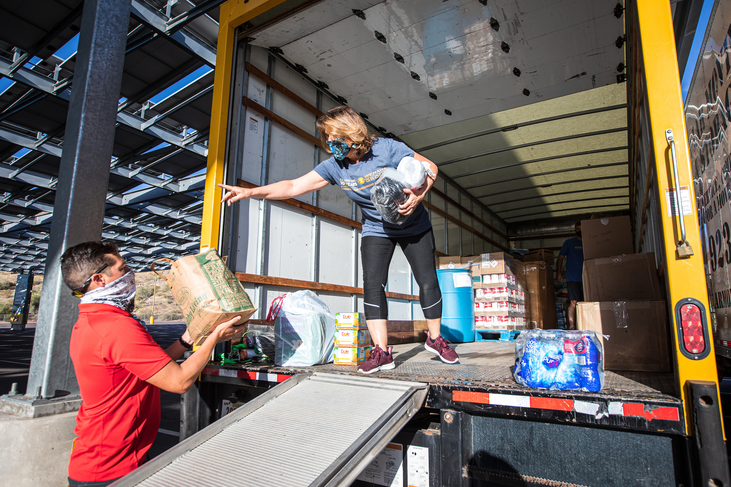 woman standing in a moving truck bed as a man helps load