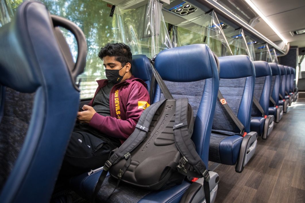 A student sits on an ASU shuttle with COVID partitions between each row