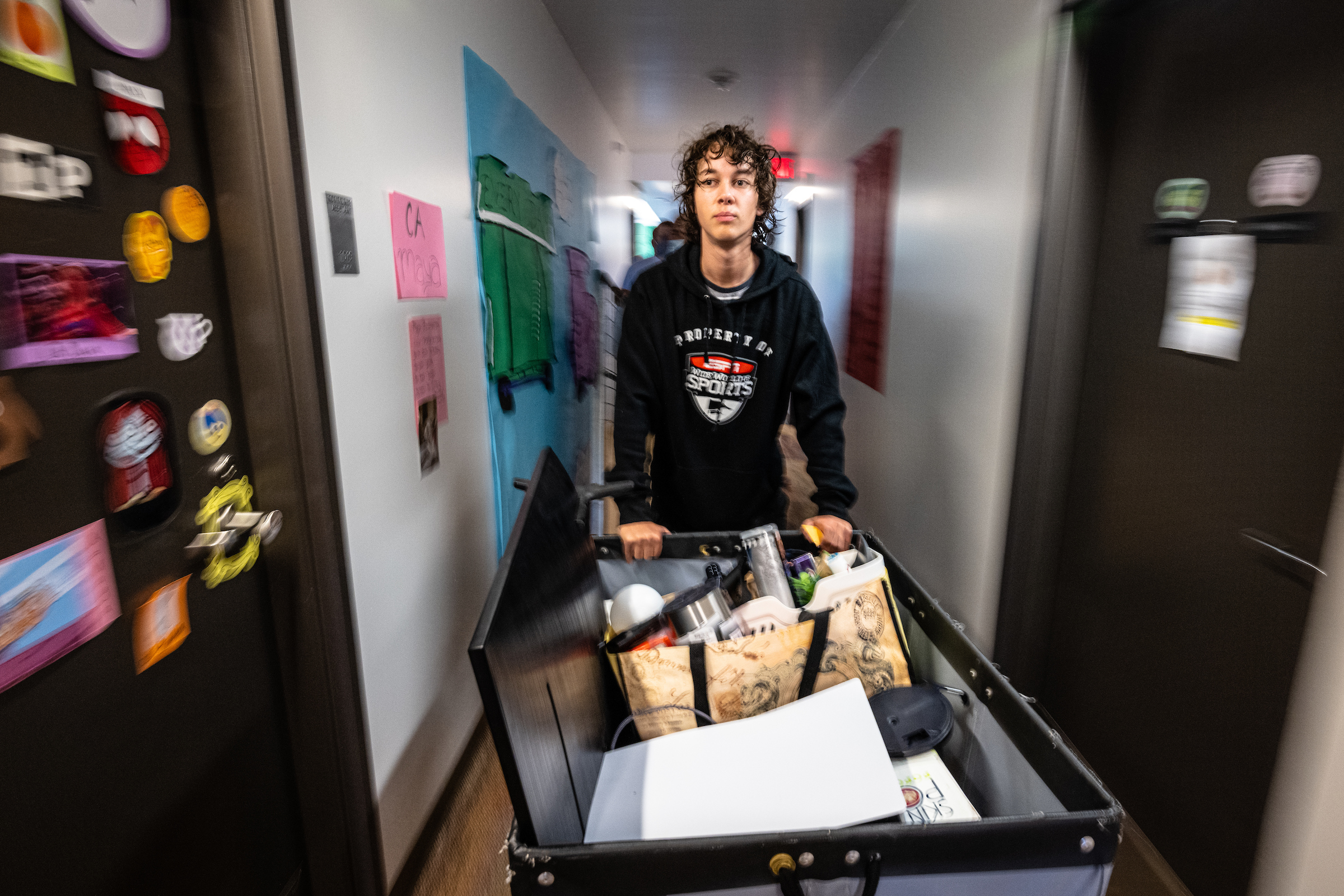 man pushing container with move-in supplies to room
