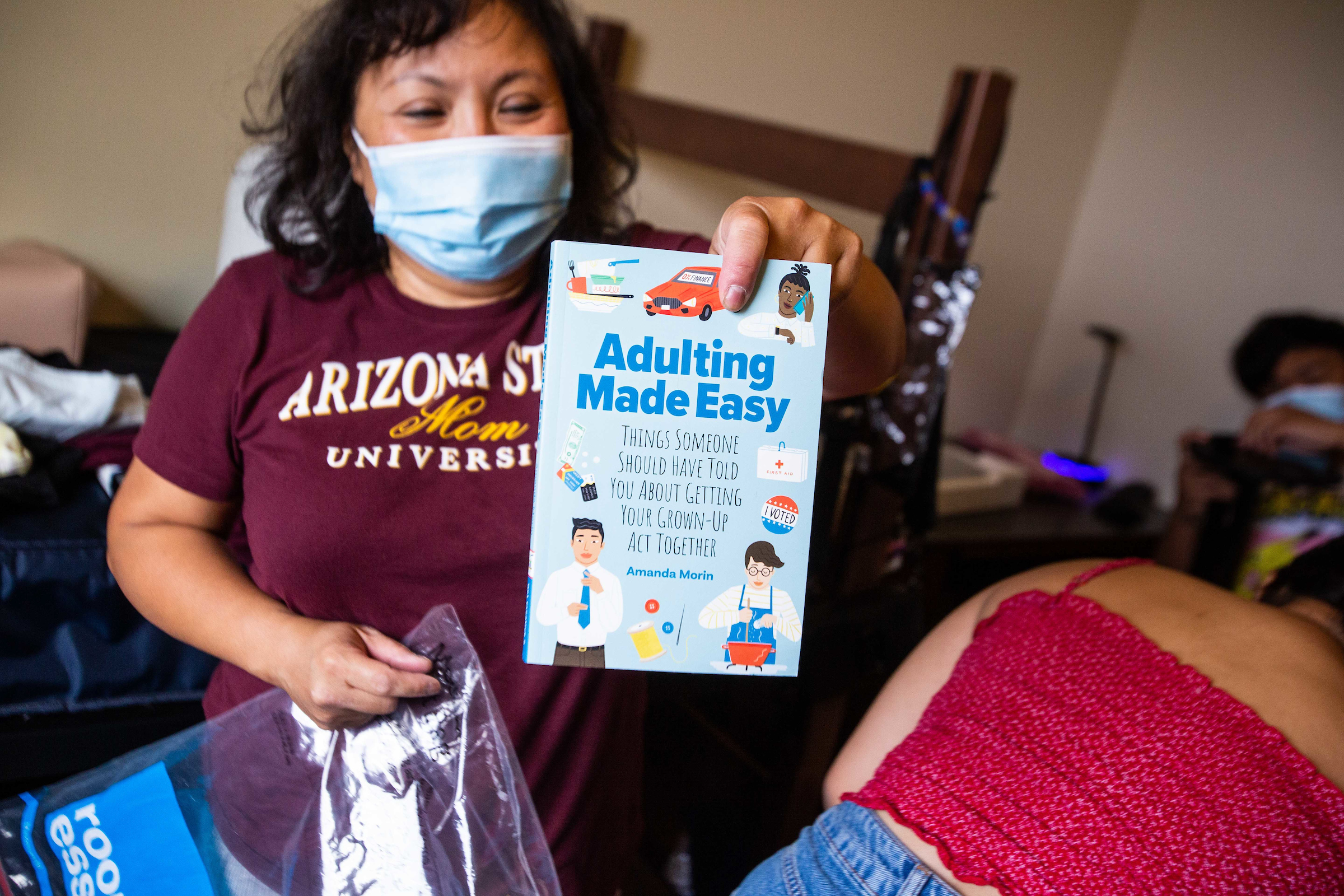 woman holding a book titled "Adulting Made Easy"