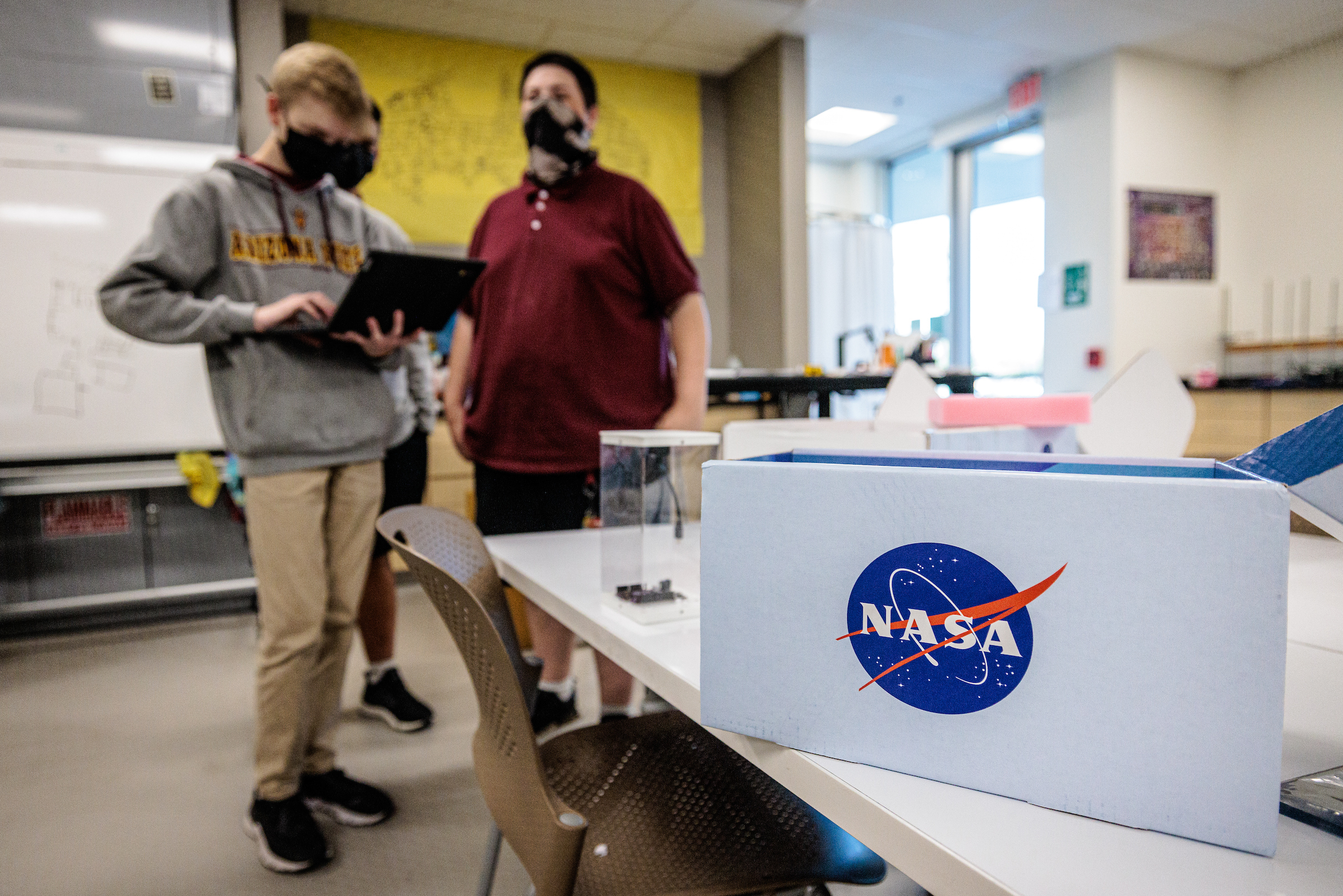 Box with NASA logo on it with students standing in background in classrom