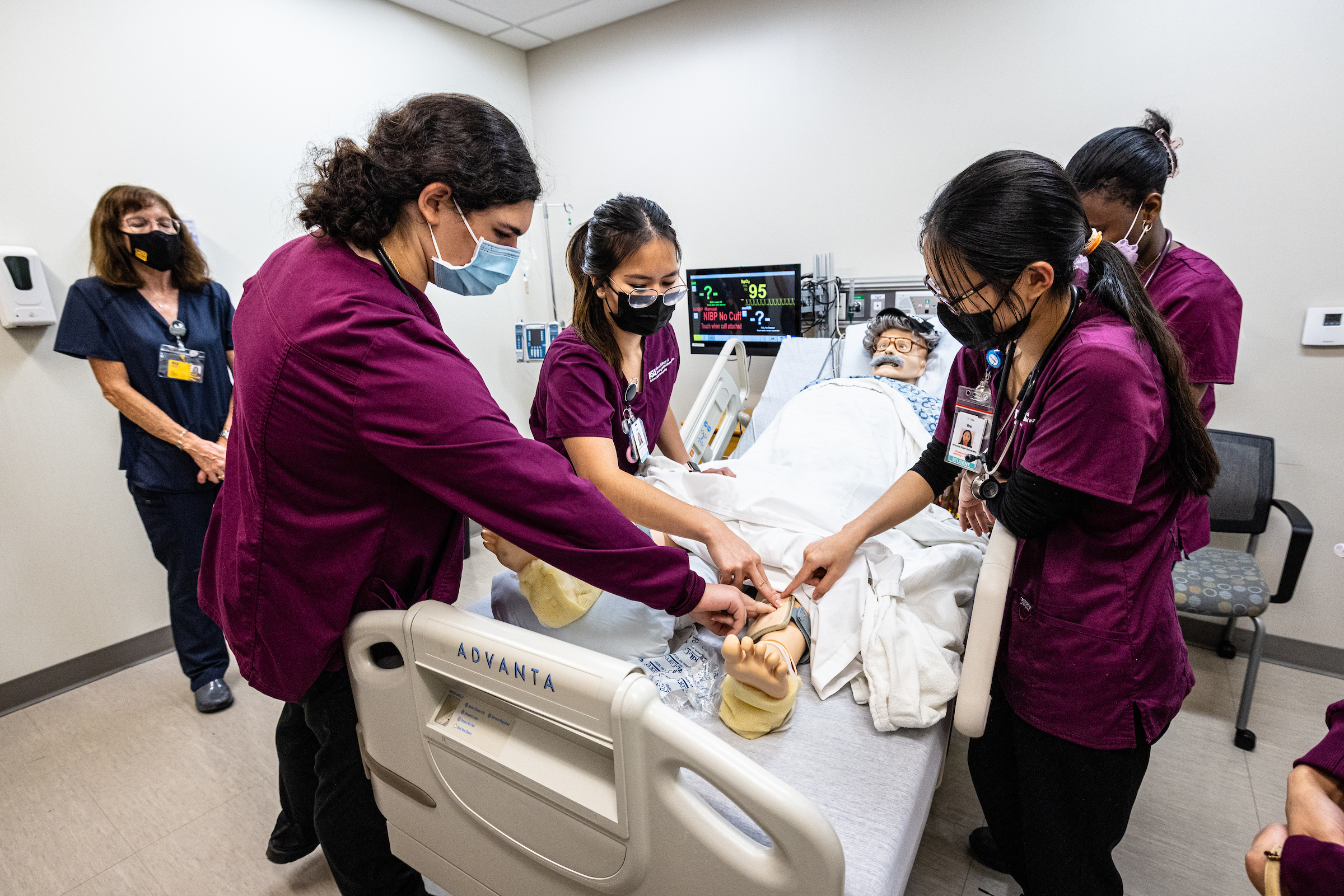 students working on a nursing manikin