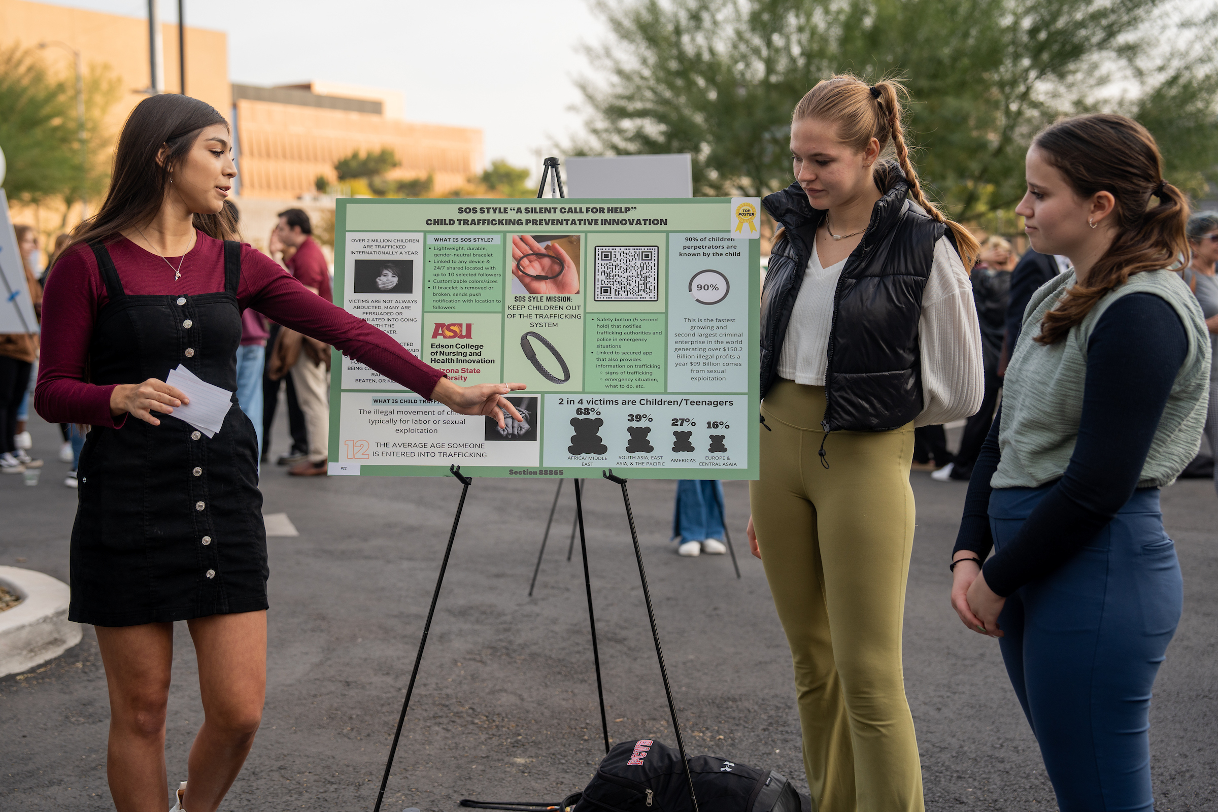 Three students standing next to poster presentation