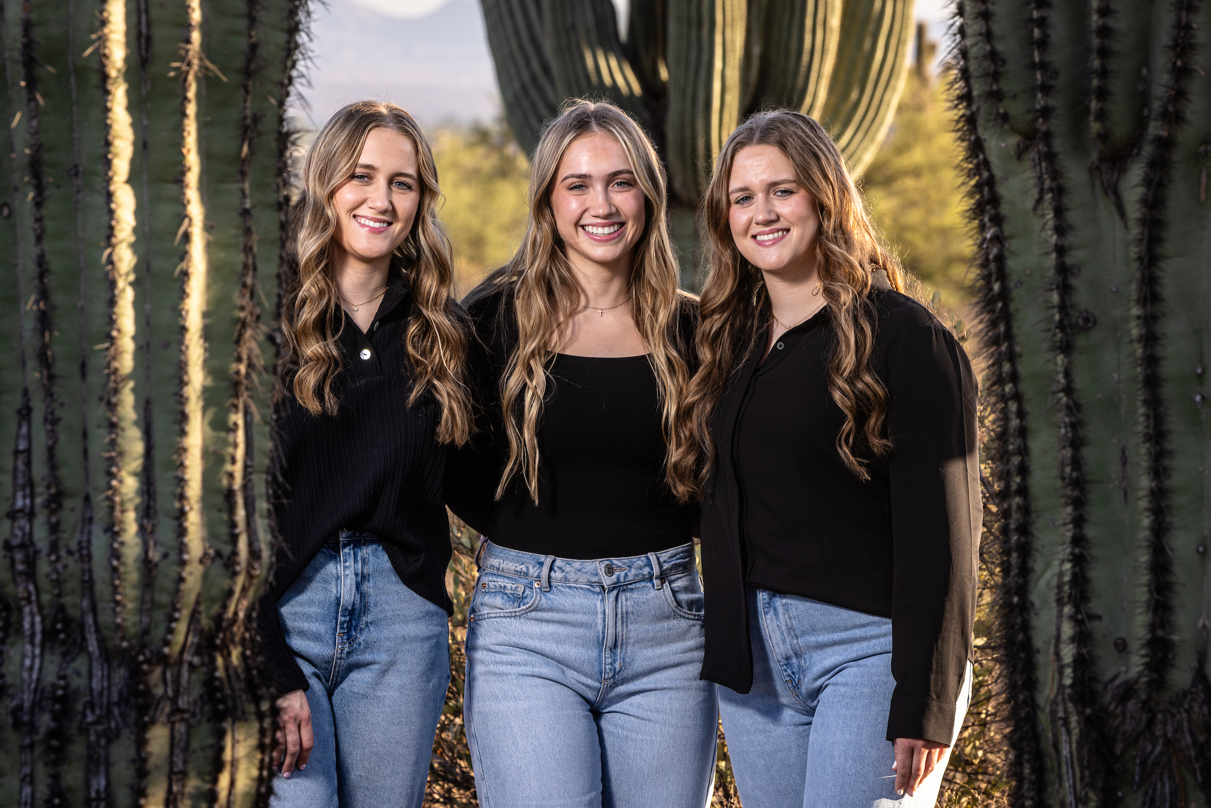 Three siblings pose in front of saguaro cacti