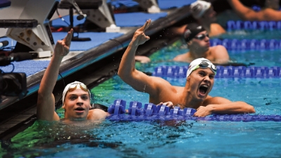 Two men's swimmers celebrate in the pool 