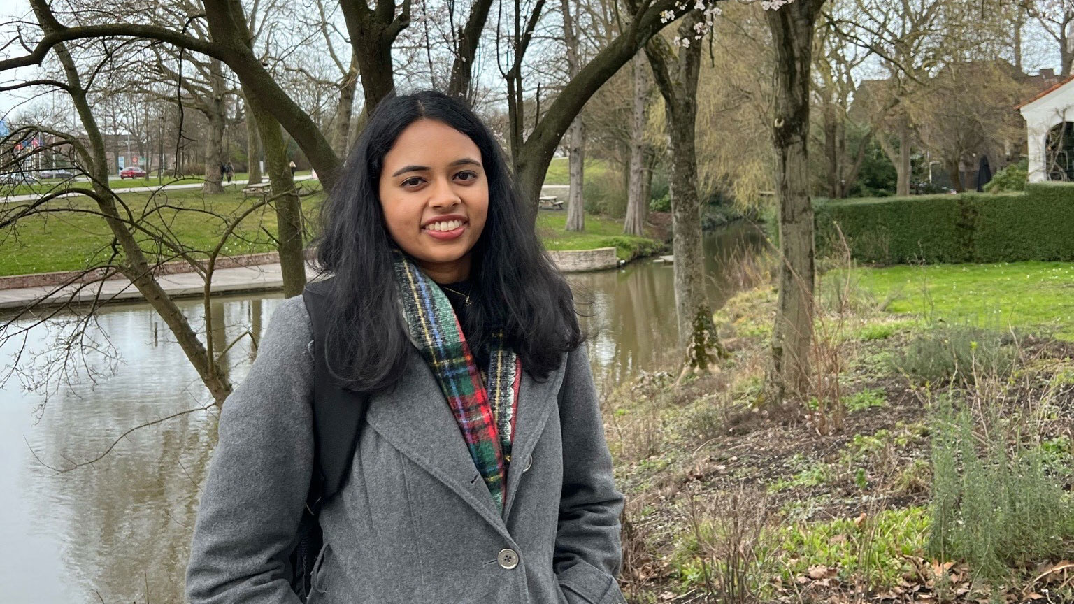 Anusha Natarajan is photographed standing in front of a tree wearing a warm jacket.