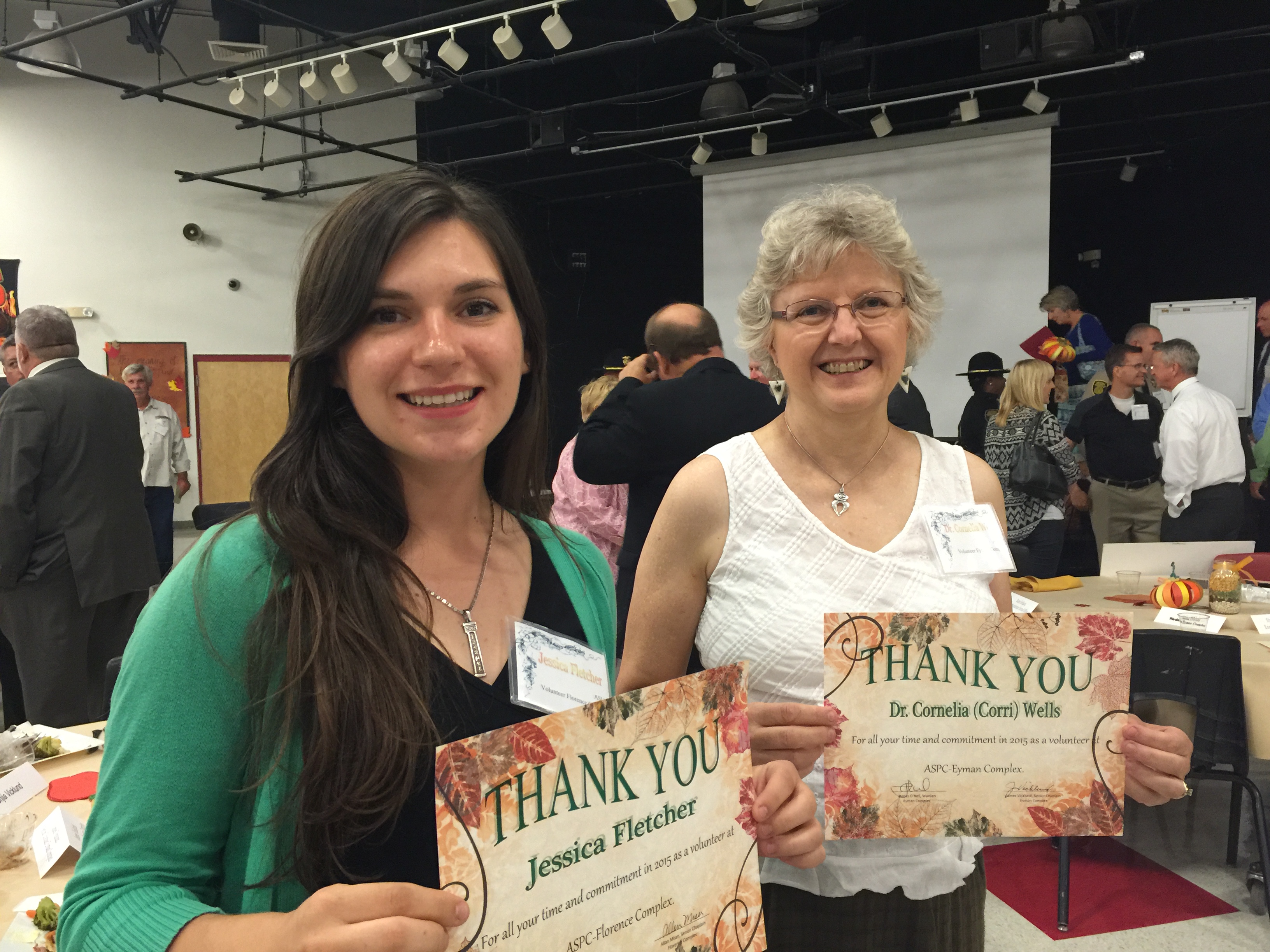 Two women hold certificates of appreciation.