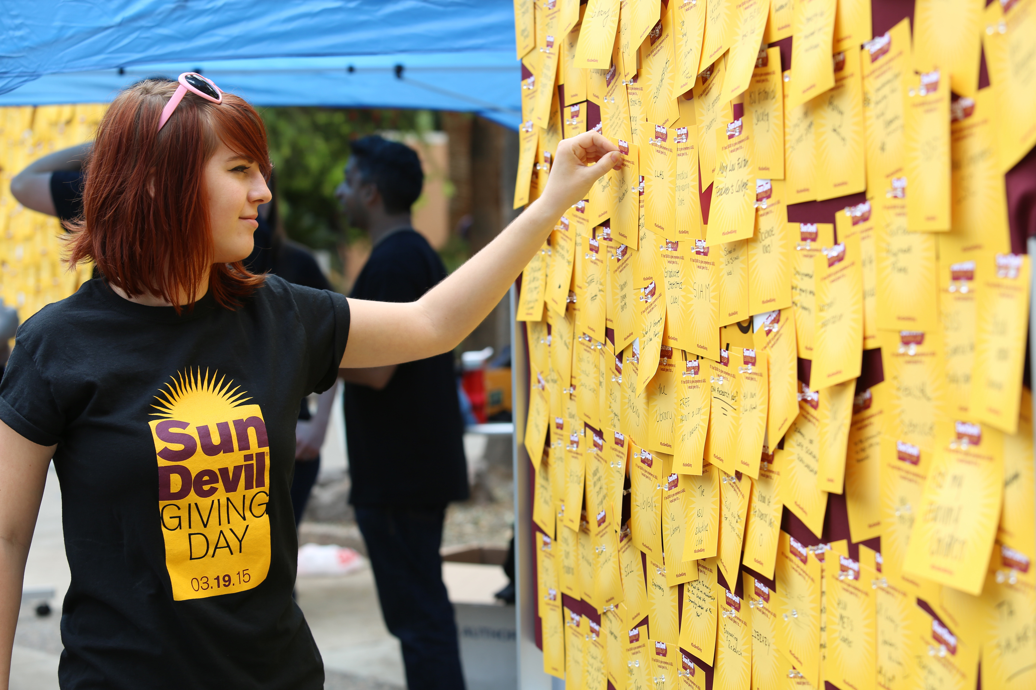 A student participates in Sun Devil Giving Day by pinning a note to a board.