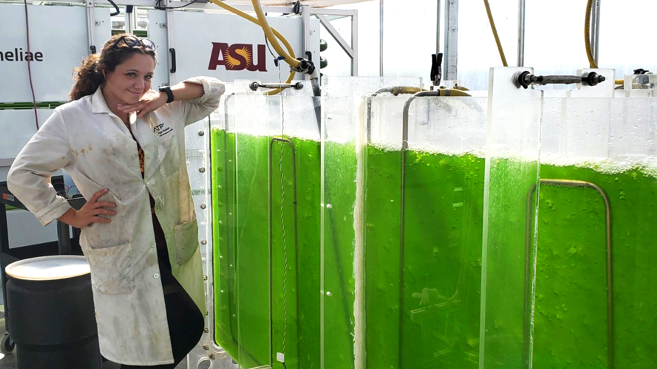 woman posing next to algae tanks