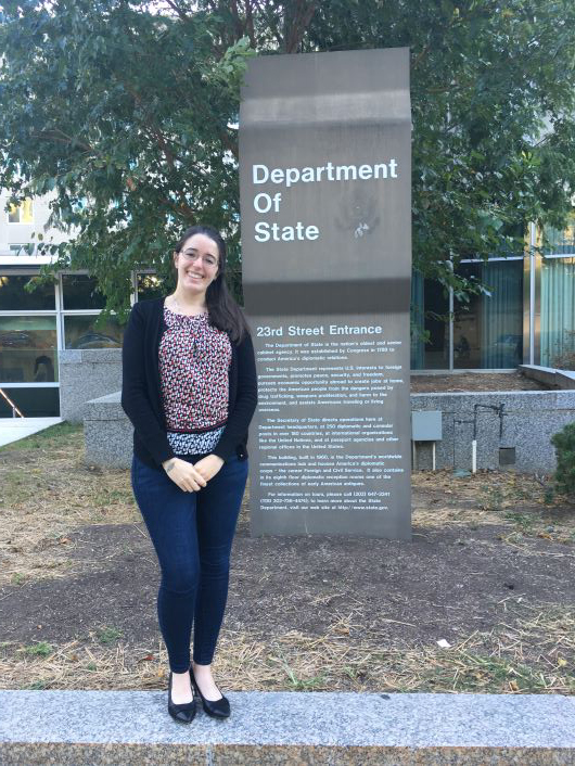 student posing in front of Department of State sign