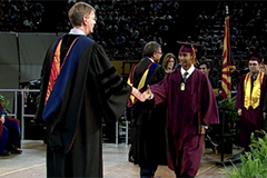 graduate walking across stage, shaking hand with dean