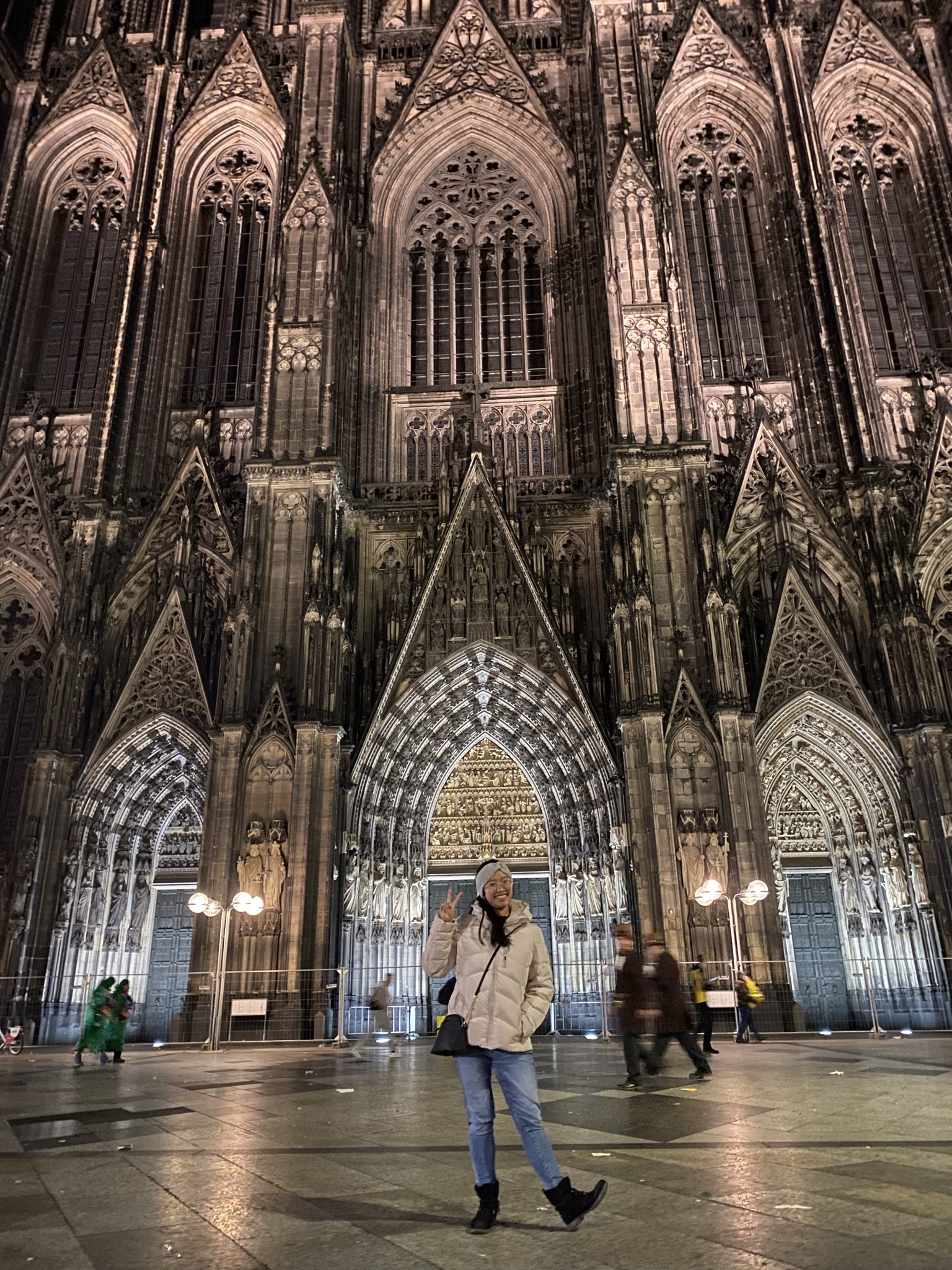 Monica Orillo visits Cologne Cathedral in North Rhine-Westphalia. The church's arching architecture extends so high in the background behind her that it stretches past the edges of the photo.