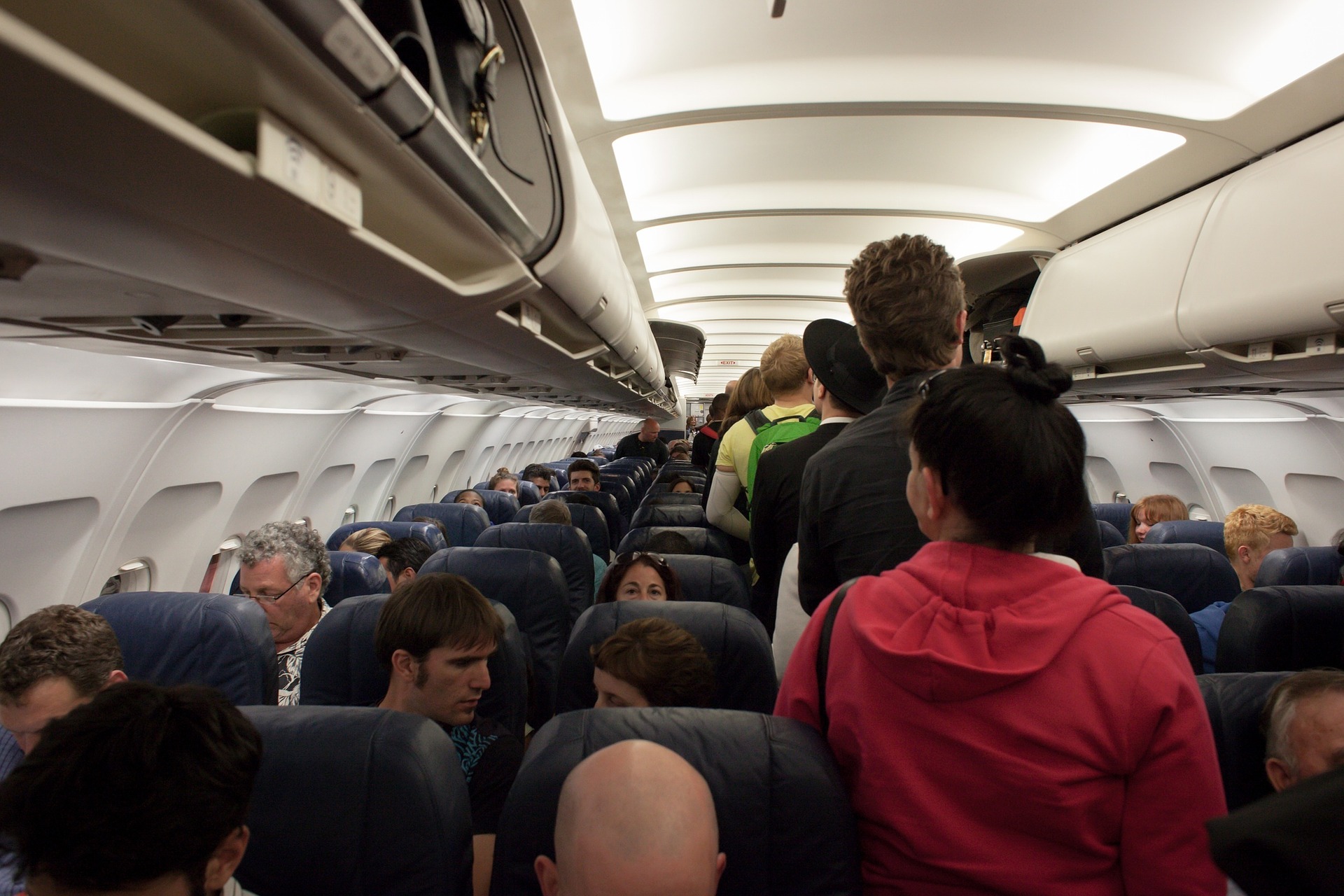 photo of passengers standing in plane aisle