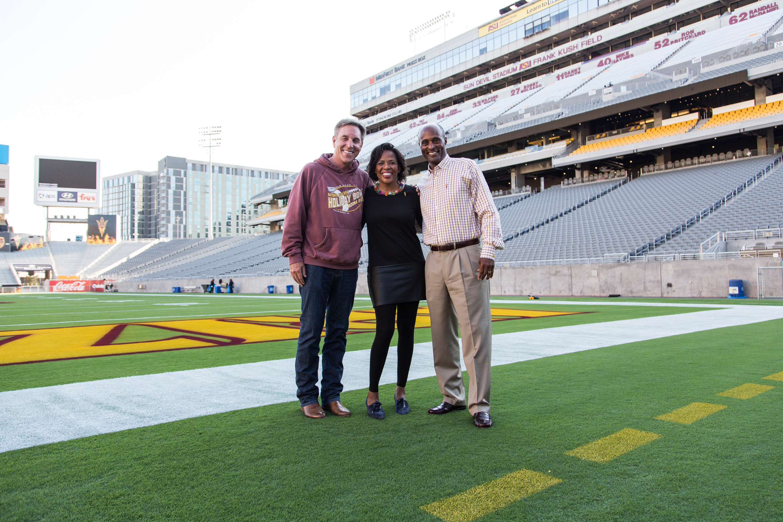 three people posing on stadium field