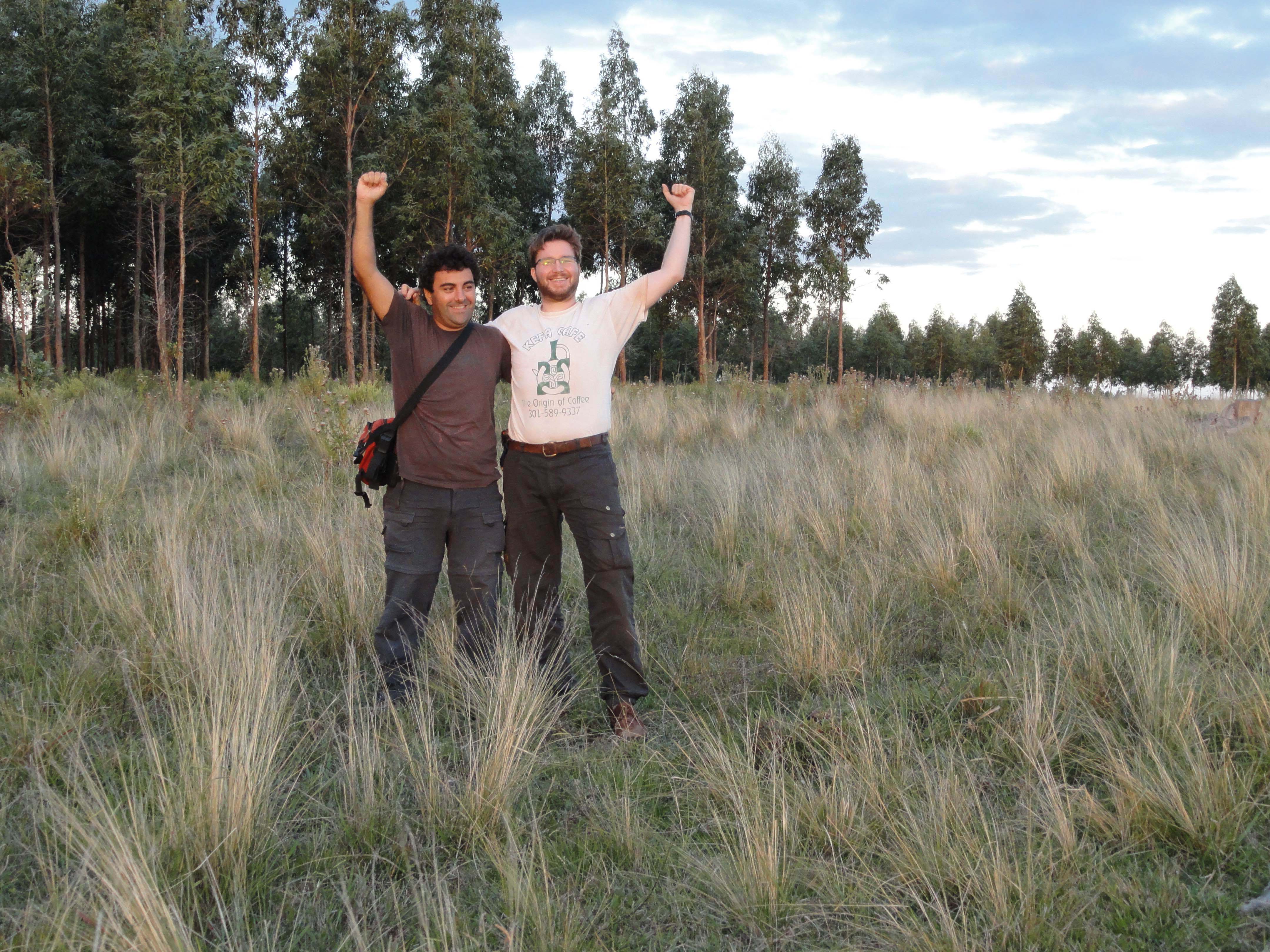 two men in a field raising their arms in the air