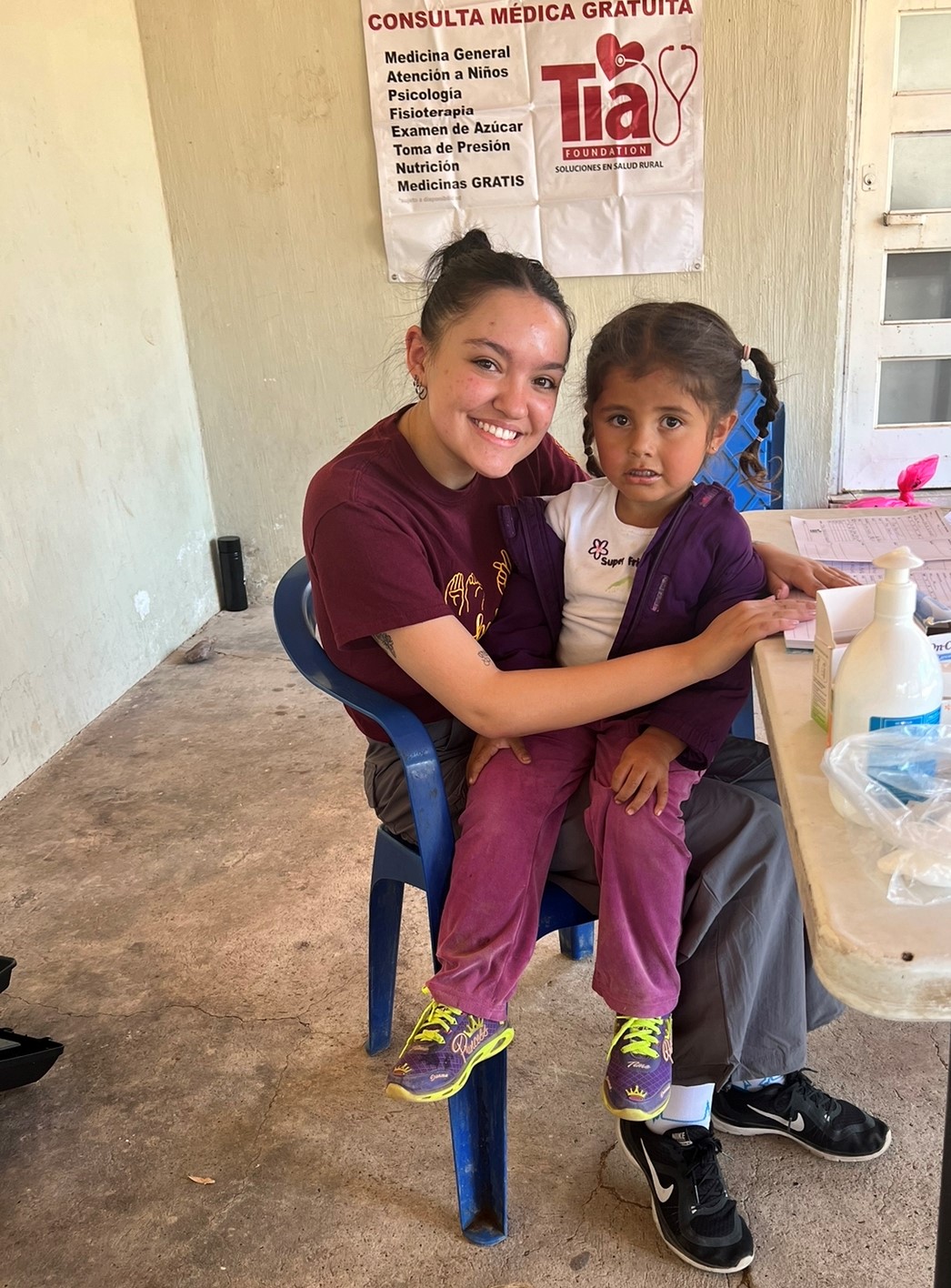 Esperanza Biggs smiles at the camera with a little girl on her lap at a community health center in Mexico