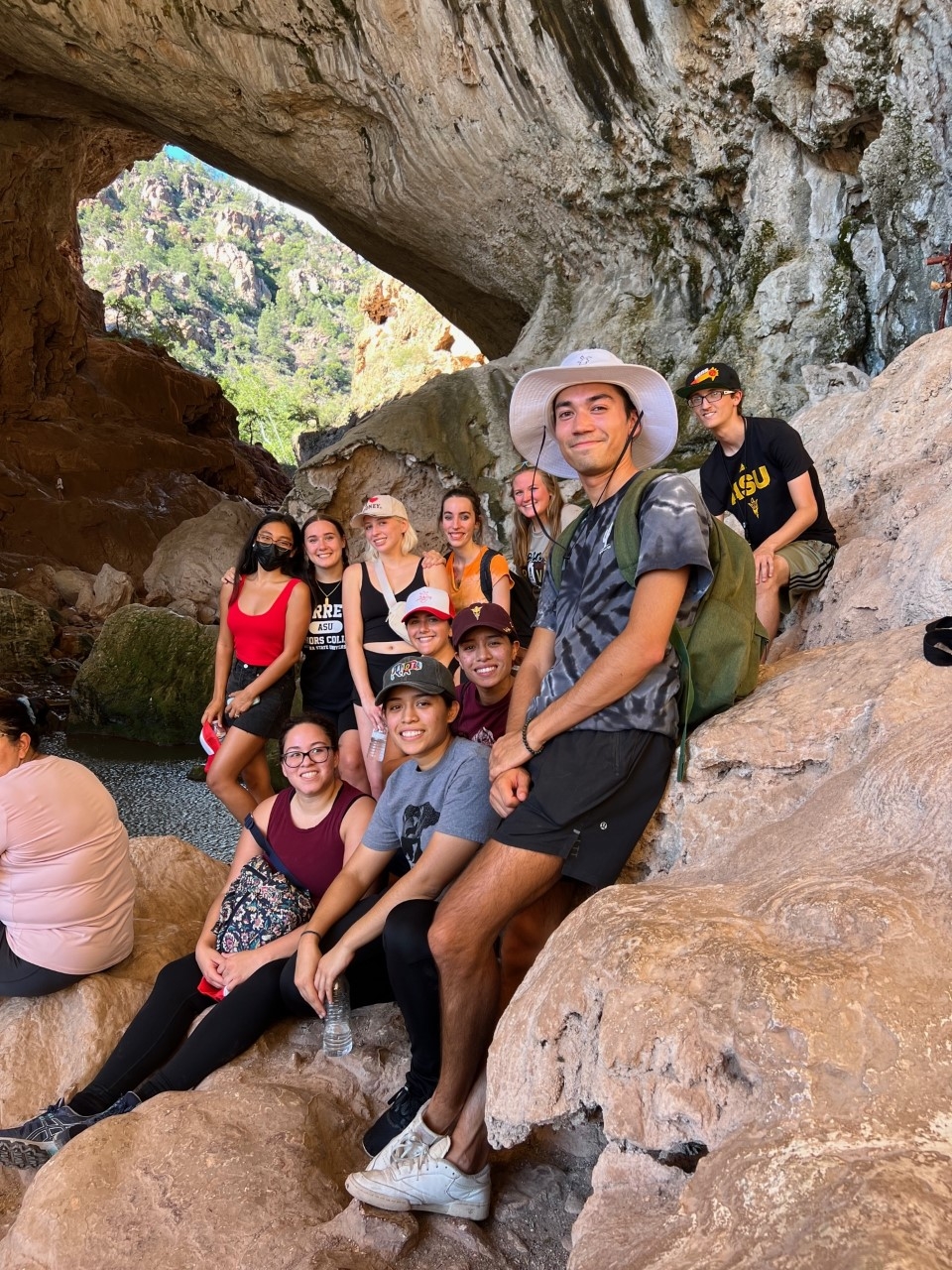Group of students gathered on a rick formation, posing for a photo with a park ranger.