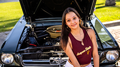Young woman sitting in front of classic car