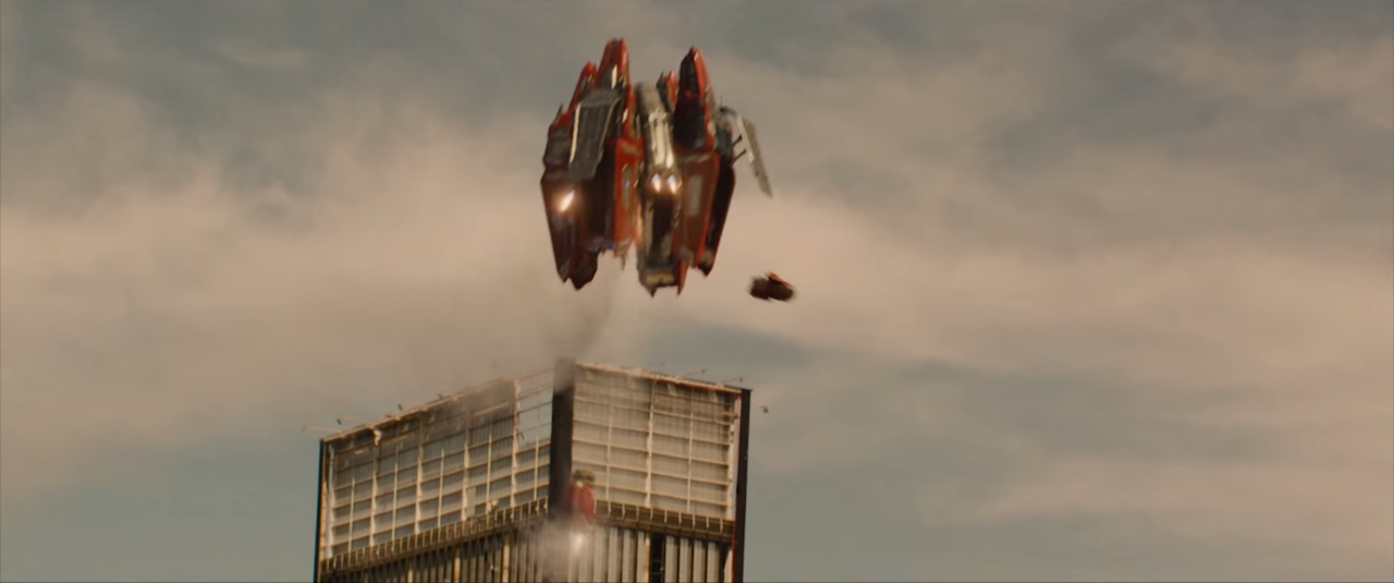 A flying machine bursts out of a building.