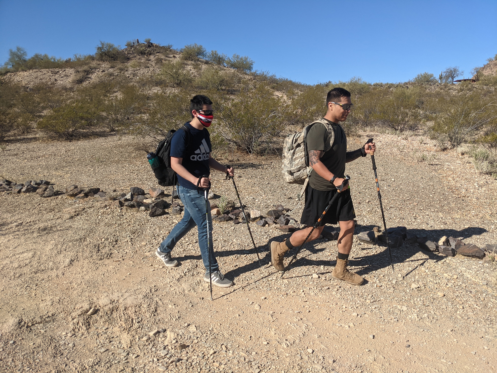 two people hiking a trail using poles