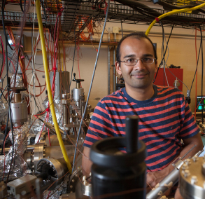 Portrait of Siddarth Karkare, an assistant professor in ASU’s Department of Physics, in a lab, surrounded by wires.