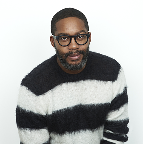 Portrait of Black man wearing glasses and a black and white striped sweater