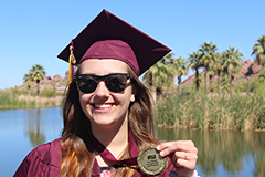 woman posing in cap and gown with medal