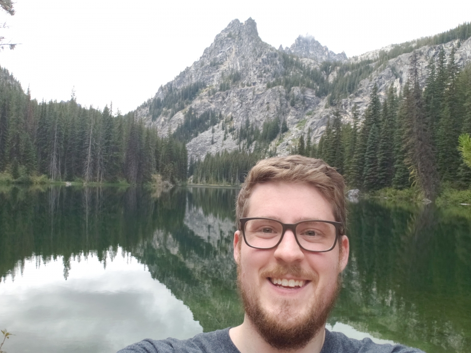 man smiling with mountain and trees in the background