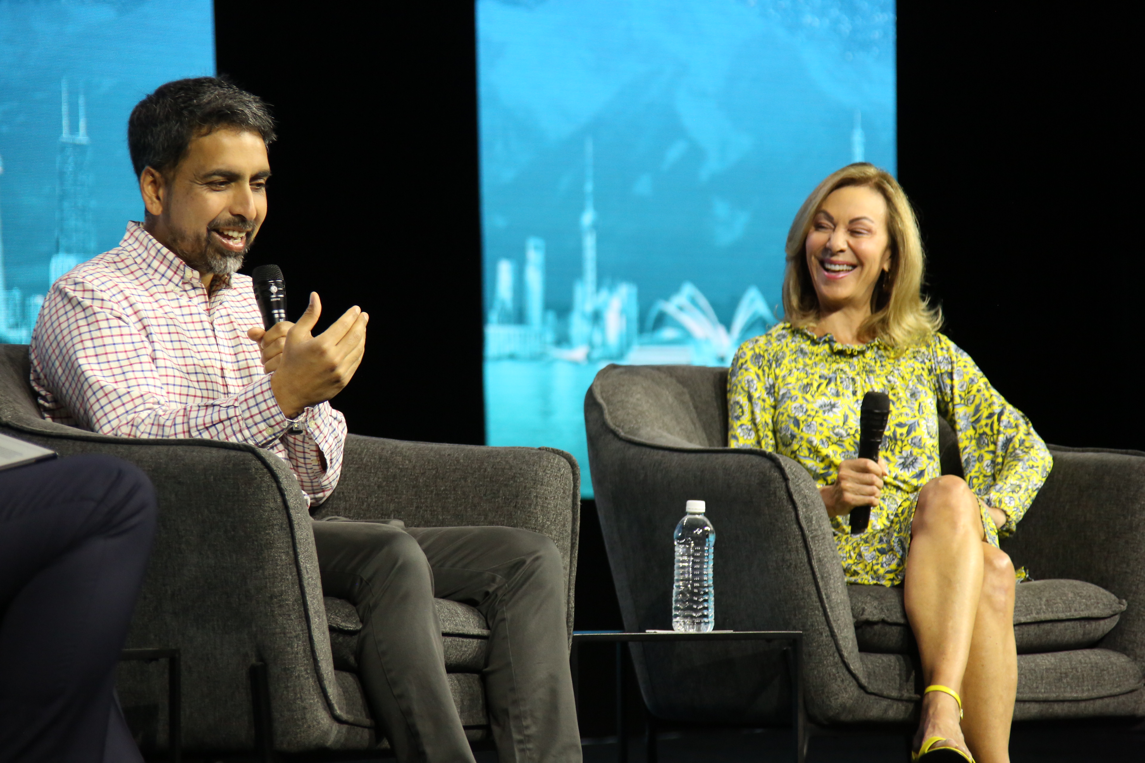 Two people smiling and talking on stage during panel