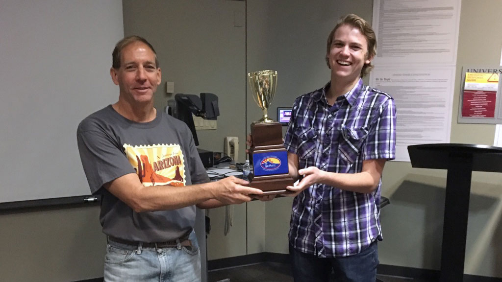 A professor and a student hold a trophy.
