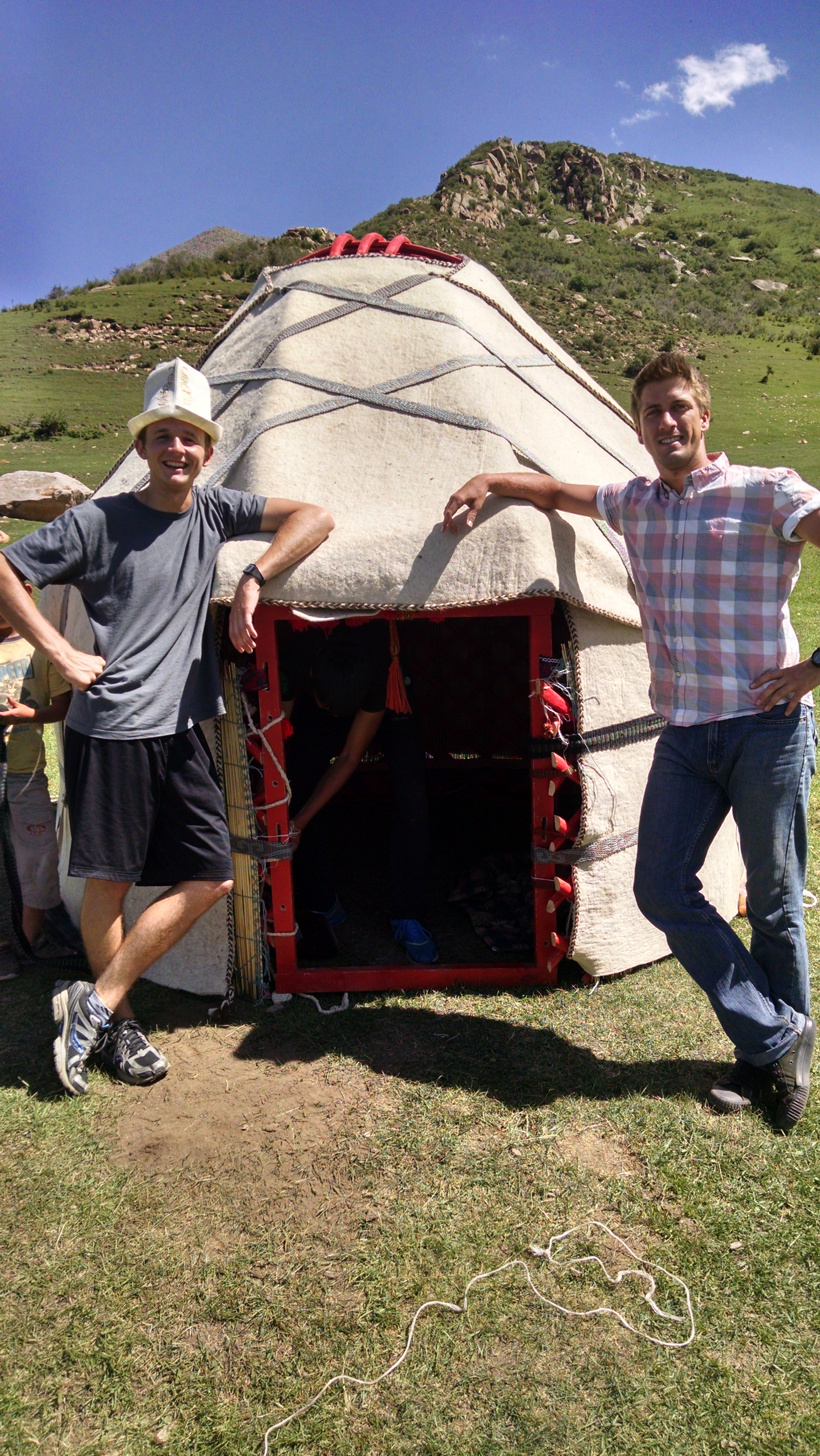 two men standing outside of a yurt