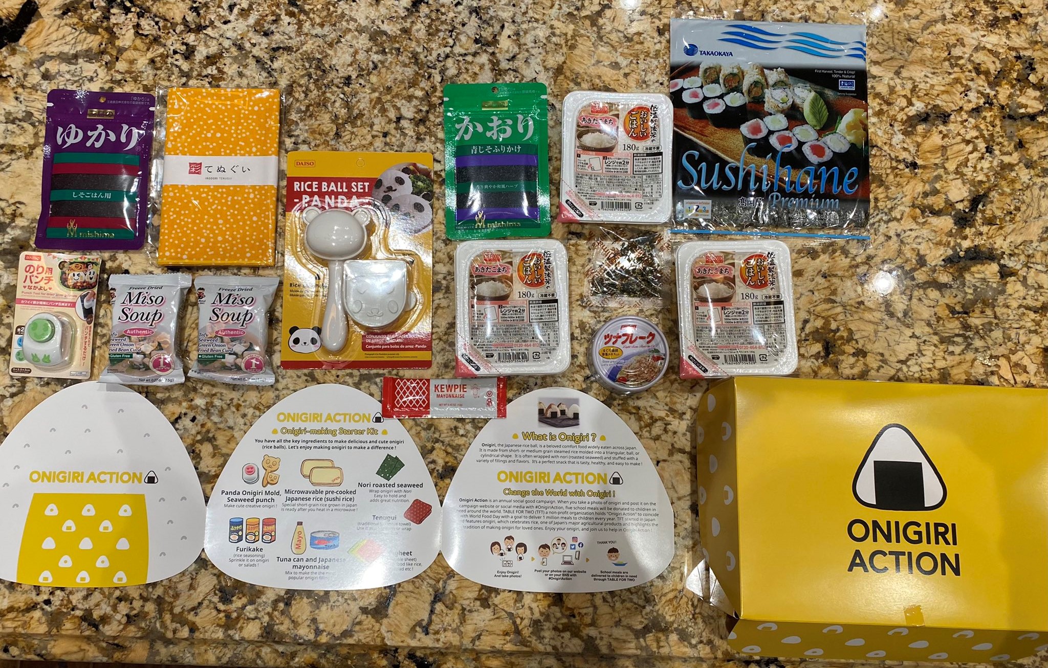 Ingredients and tools for making onigiri, Japanese rice balls, are laid out on a counter. The ingredients include instant rice, canned tuna and sheets of dried seaweed. There is also a rice press that shapes the rice into the shape of a panda.