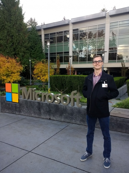 Richard Rigby, an electrical engineering alumnus, poses in front of a Microsoft sign.