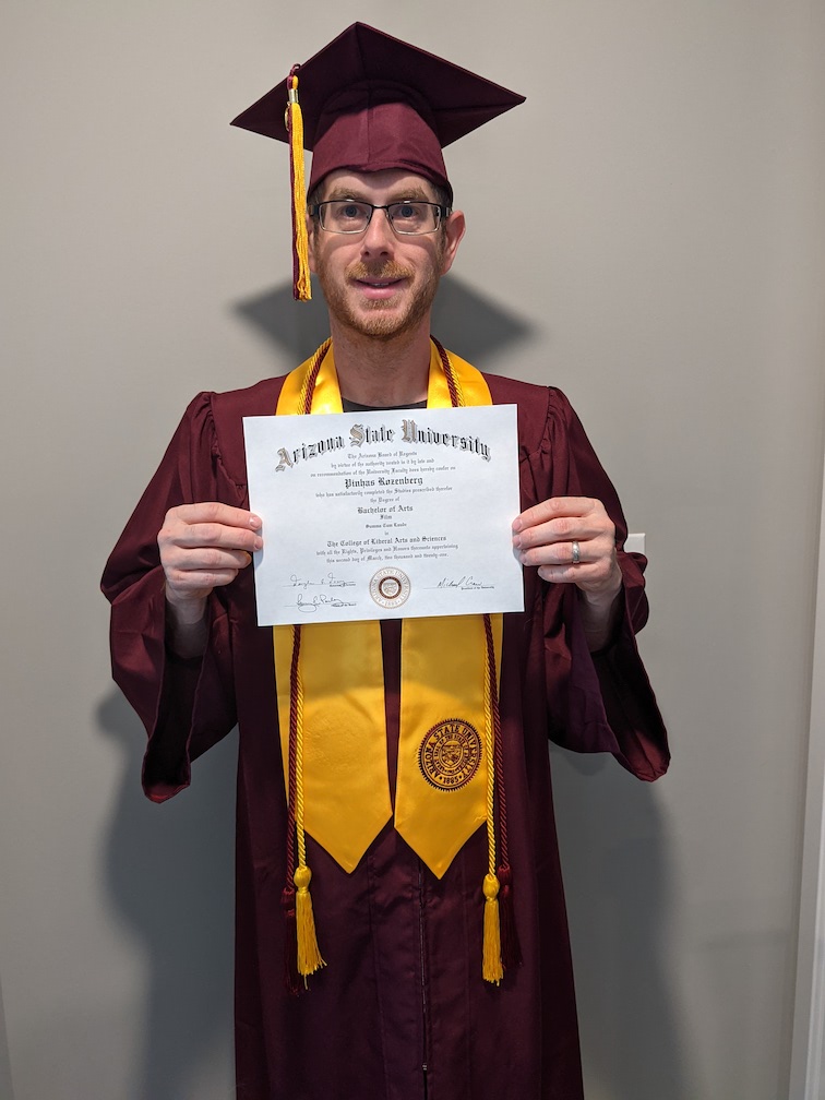 Peter Rozenberg holds his diploma in his ASU regalia