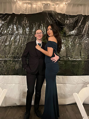 Two people wearing eveningwear pose for a photo.