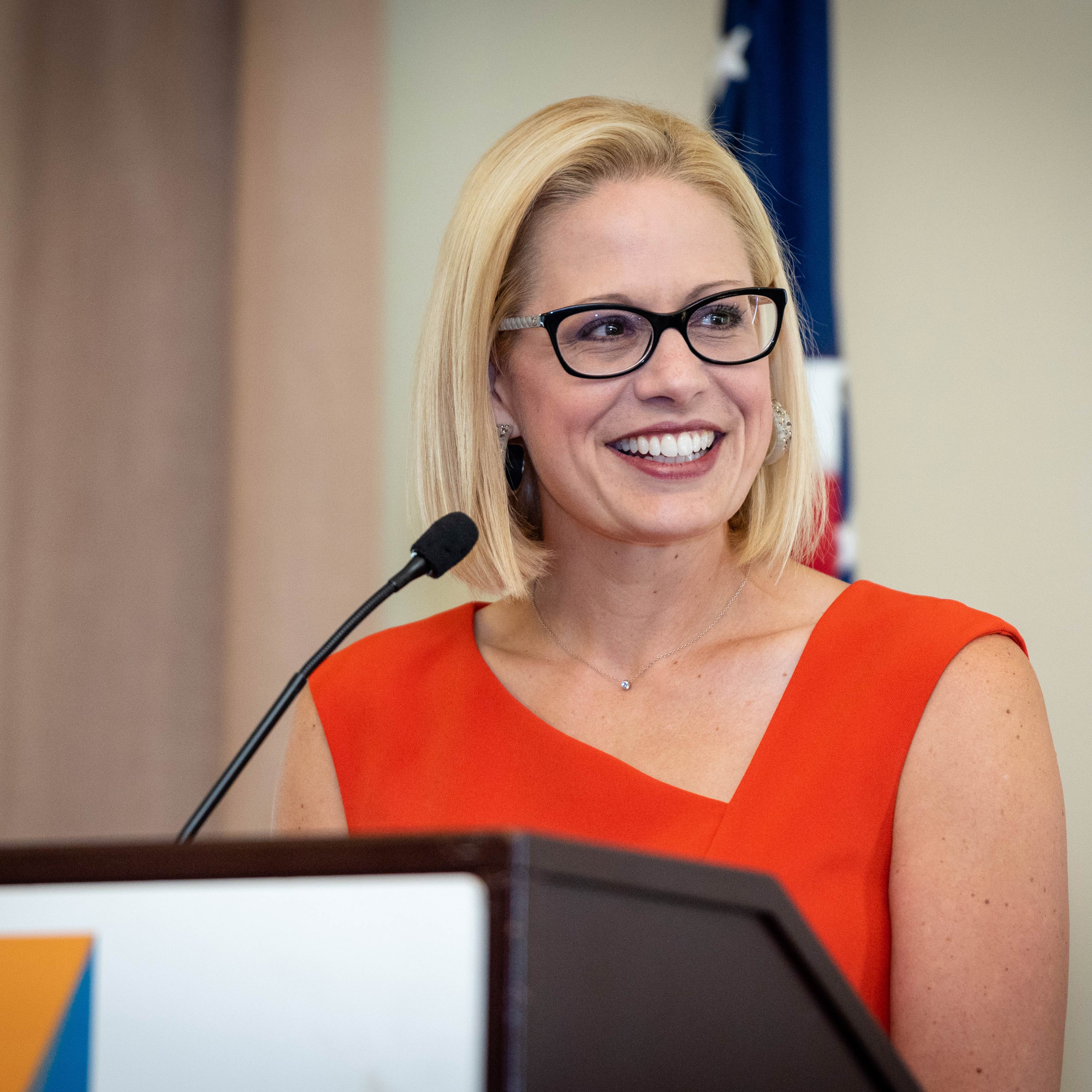 Blonde woman in glasses and orange dress