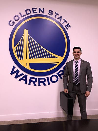 student standing in front of Golden State Warriors sign