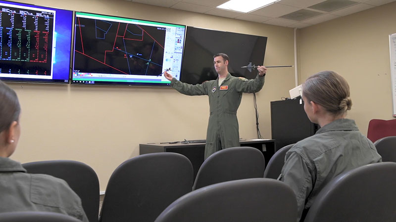 A Luke Air Force Base flight instructor trains student pilots during a post-flight debriefing session. 