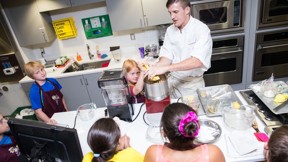 chef showing young students how to use kitchen tools