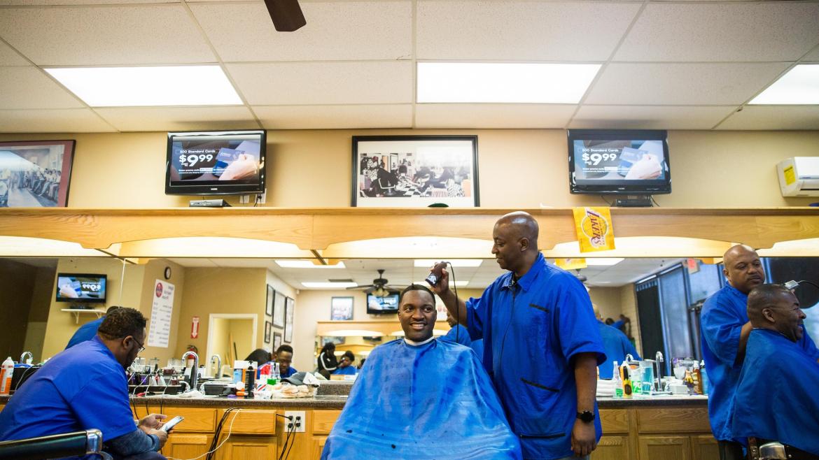 Men have their hair cut in a barbershop.