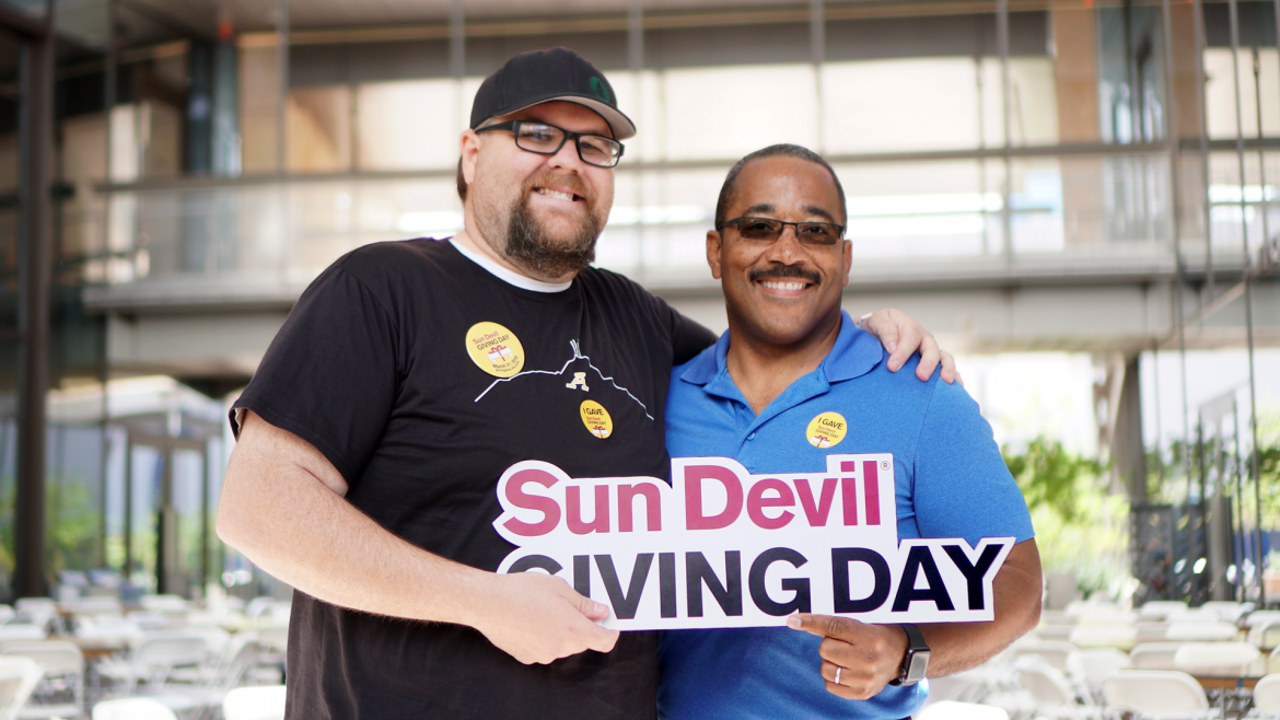 Two men hold a sign that reads "Sun Devil Giving Day."