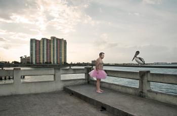 photographer and ASU alum Bob Carey in a tutu on a pier with a bird