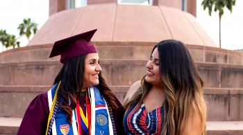 Woman wearing ASU graduation regallia and smiling at a family member.