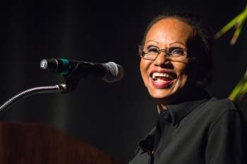 The late ASU Professor Elsie Moore smiling while speaking into a microphone.